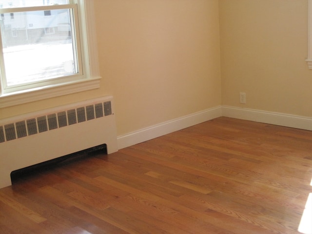 empty room featuring wood-type flooring and radiator