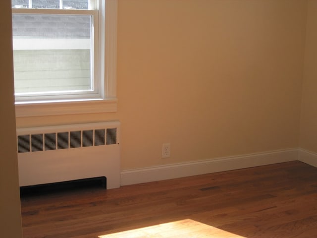 spare room featuring hardwood / wood-style flooring and radiator