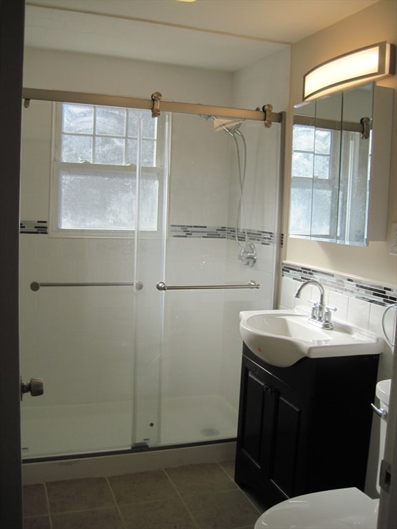 bathroom with tile patterned flooring, vanity, an enclosed shower, and toilet