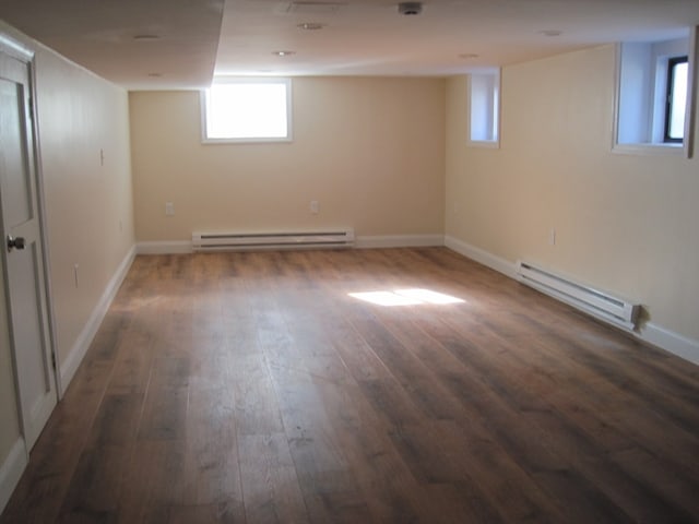 basement featuring dark hardwood / wood-style flooring and baseboard heating