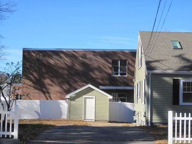 rear view of property featuring a storage unit