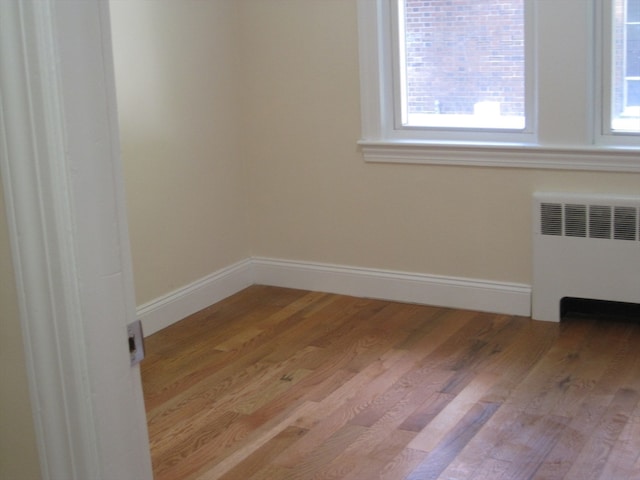 spare room featuring radiator and light hardwood / wood-style floors