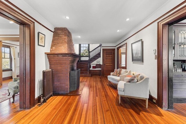 10 Quissett, Falmouth, MA 02543 - living room with radiator, stairs, wood-type flooring, crown molding, and a fireplace
