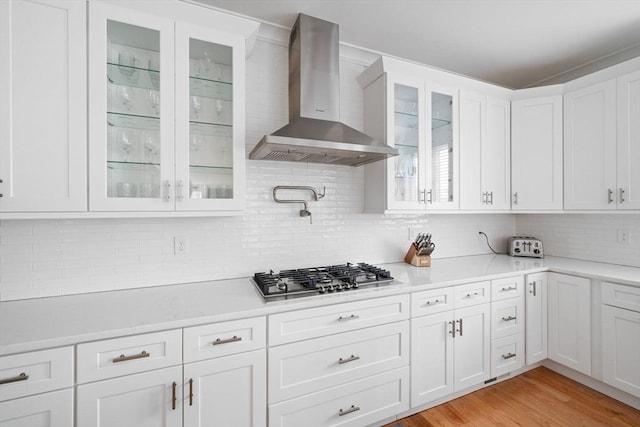 kitchen featuring white cabinetry, stainless steel gas stovetop, light hardwood / wood-style flooring, and wall chimney range hood