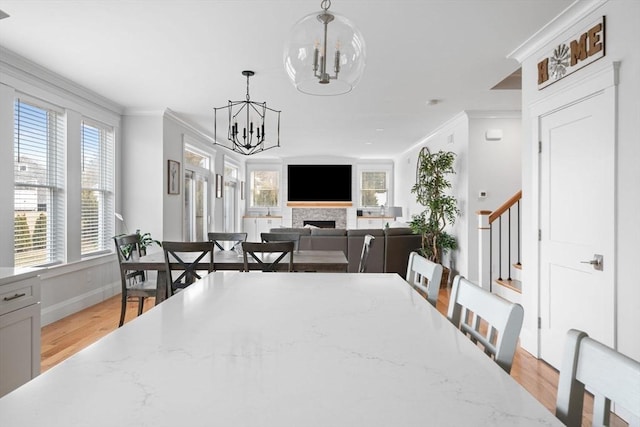 dining space with a notable chandelier, ornamental molding, and light hardwood / wood-style floors