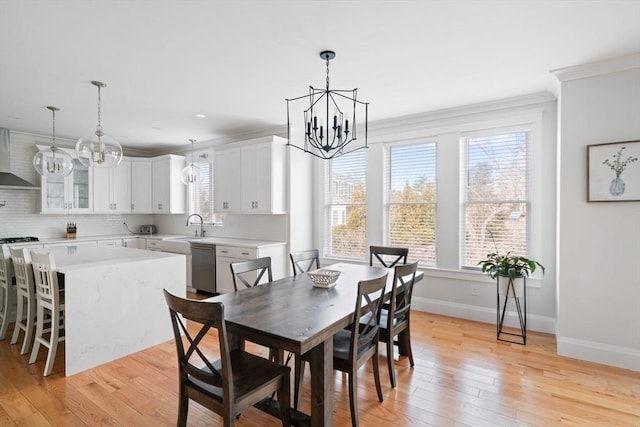 dining space featuring sink, ornamental molding, light hardwood / wood-style floors, and a chandelier