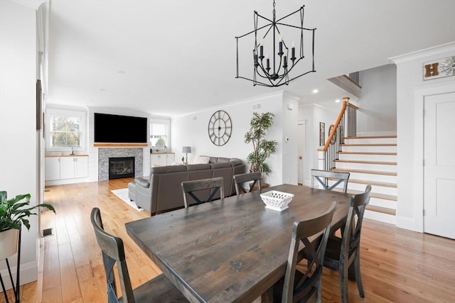 dining space with crown molding, a chandelier, and light hardwood / wood-style flooring