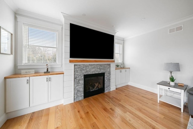 unfurnished living room featuring crown molding, plenty of natural light, and light hardwood / wood-style floors