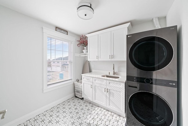 washroom with cabinets, stacked washer and clothes dryer, and sink