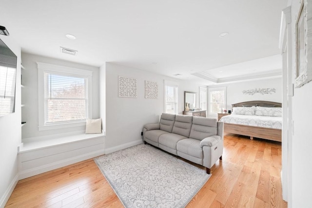 bedroom featuring a raised ceiling and light wood-type flooring