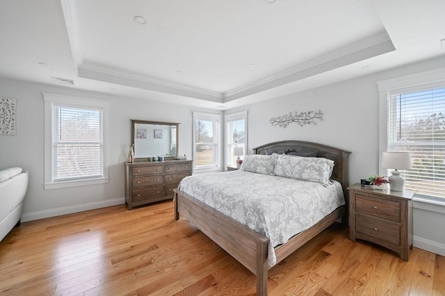 bedroom with crown molding, a raised ceiling, and light wood-type flooring