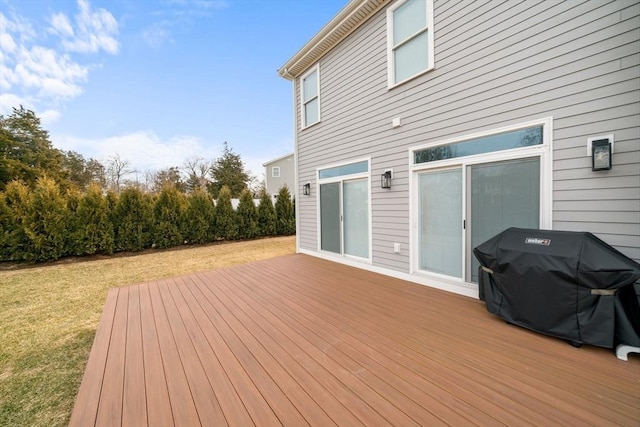 wooden deck featuring a grill and a lawn