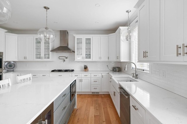 kitchen with dishwasher, white cabinetry, hanging light fixtures, gas stovetop, and wall chimney exhaust hood