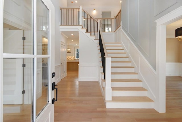 stairs featuring recessed lighting, wainscoting, wood finished floors, and a decorative wall