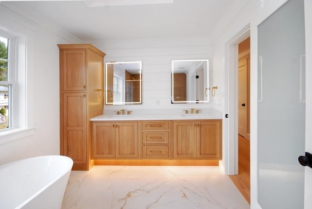 full bathroom with a freestanding tub, marble finish floor, and a sink