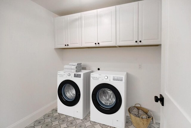 laundry area featuring washing machine and clothes dryer, cabinet space, and baseboards