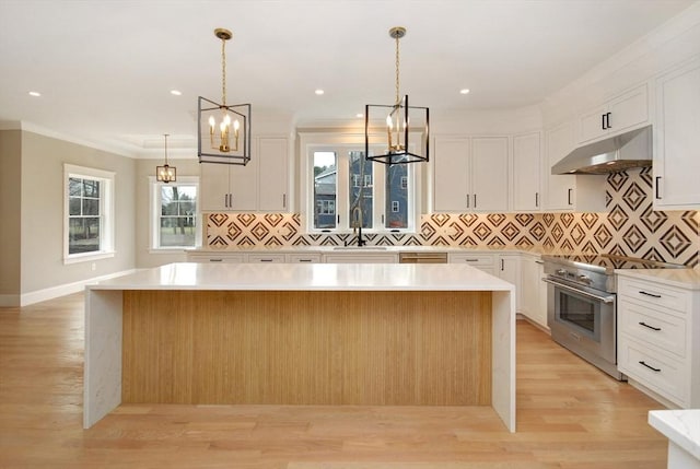 kitchen featuring a sink, high end range, a chandelier, and under cabinet range hood