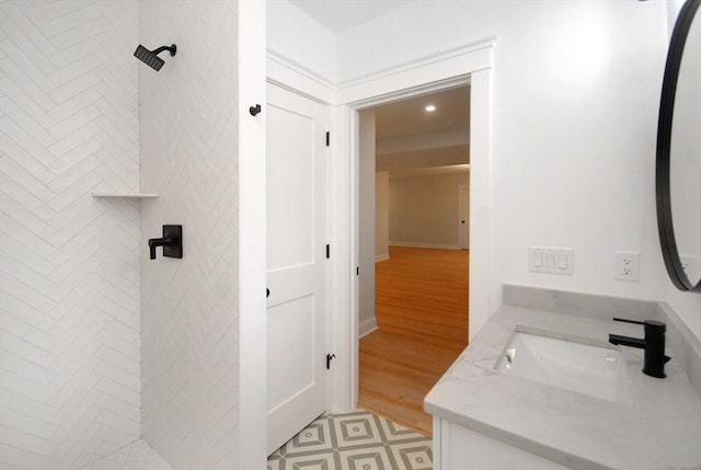 bathroom featuring a tile shower, recessed lighting, wood finished floors, and vanity