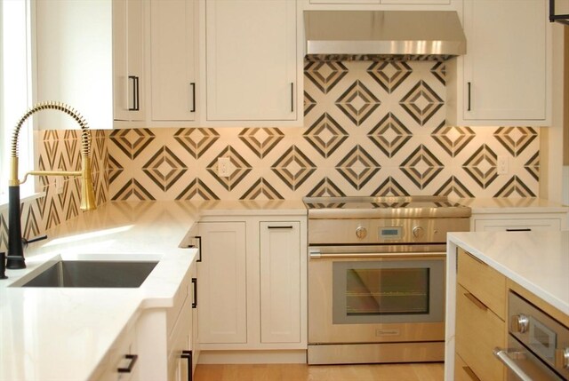 kitchen with a sink, decorative backsplash, light stone counters, extractor fan, and high end stainless steel range oven
