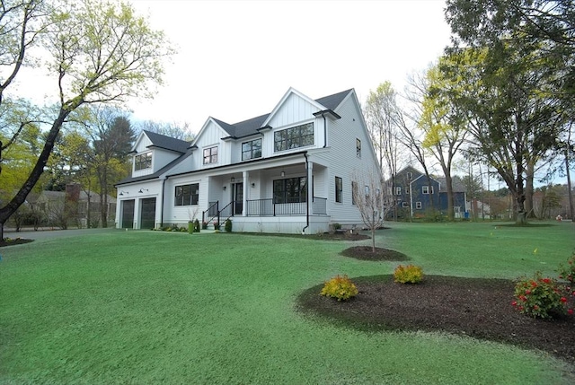rear view of property featuring a garage, a porch, board and batten siding, and a yard
