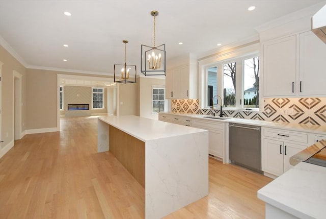 kitchen featuring a sink, tasteful backsplash, crown molding, a center island, and stainless steel dishwasher