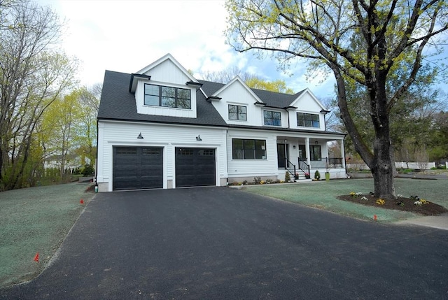 modern inspired farmhouse featuring a garage, a porch, aphalt driveway, and a front lawn
