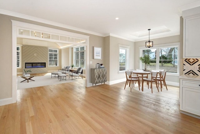 dining area with a fireplace, ornamental molding, light wood-style flooring, and baseboards