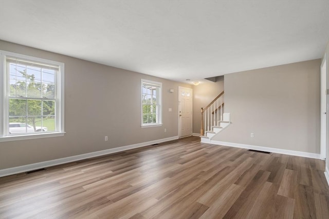 unfurnished room featuring wood-type flooring and a healthy amount of sunlight