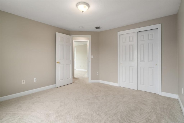 unfurnished bedroom featuring light colored carpet and a closet