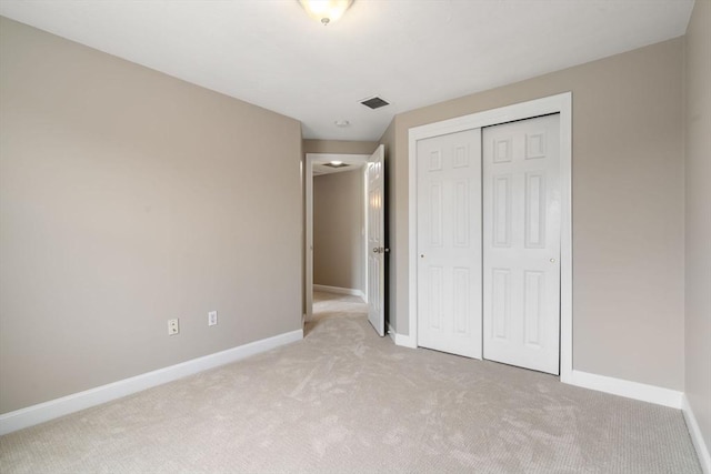 unfurnished bedroom with light colored carpet and a closet