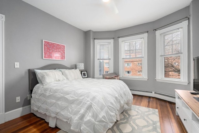 bedroom featuring a baseboard heating unit and hardwood / wood-style floors