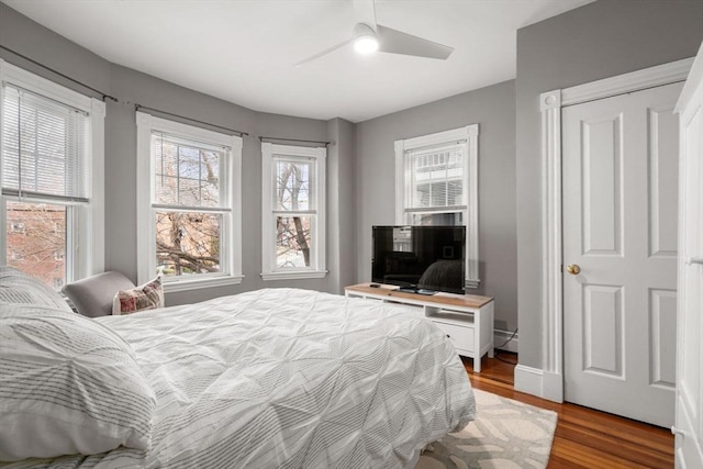 bedroom featuring baseboards, a baseboard radiator, a ceiling fan, and wood finished floors