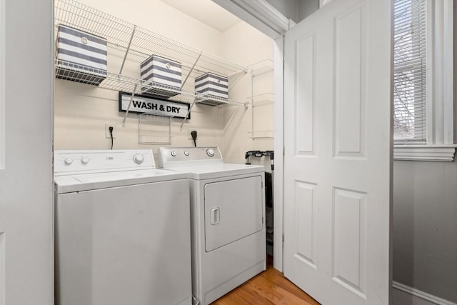 clothes washing area with light wood-style floors, laundry area, and washer and clothes dryer