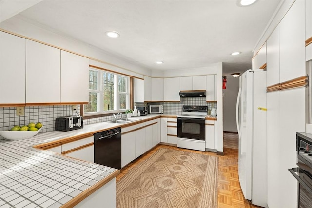 kitchen with dishwasher, electric stove, freestanding refrigerator, under cabinet range hood, and a sink