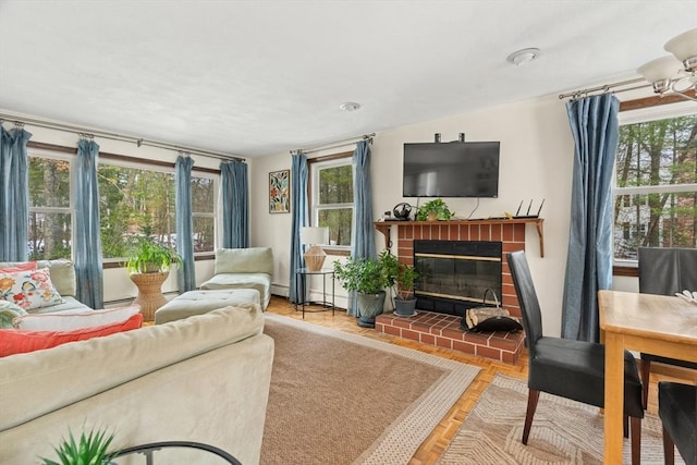 living room featuring a baseboard radiator, a brick fireplace, and a wealth of natural light