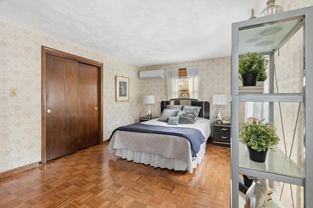 bedroom with a wall unit AC, wallpapered walls, parquet floors, and baseboards