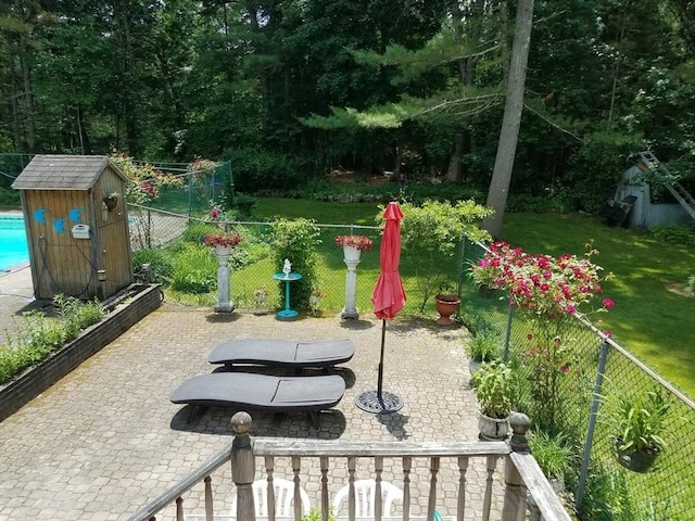 view of property's community featuring an outbuilding, fence, a yard, a patio area, and a shed