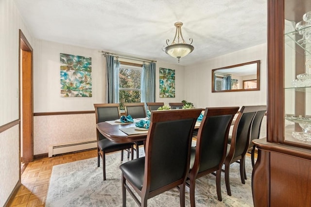 dining area featuring a baseboard heating unit, wainscoting, baseboards, and wallpapered walls