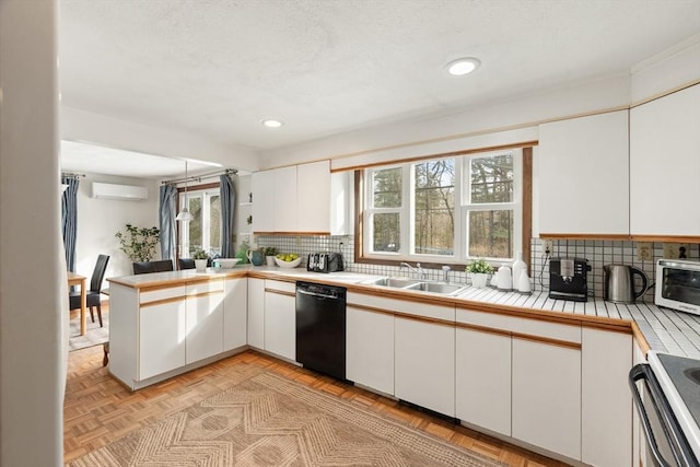 kitchen with range, dishwasher, a peninsula, an AC wall unit, and a sink