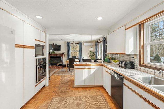 kitchen with a peninsula, black appliances, white cabinetry, and decorative backsplash