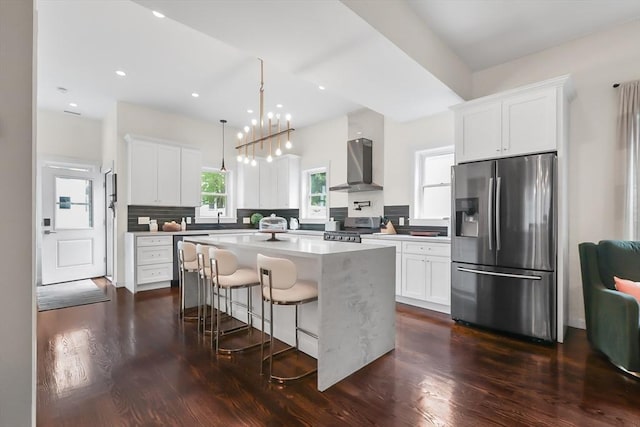 10 Wakefield Ave Unit A, Wakefield, MA 01880 - kitchen featuring stainless steel refrigerator with ice dispenser, wall chimney range hood, stove, dark wood finished floors, and a kitchen island