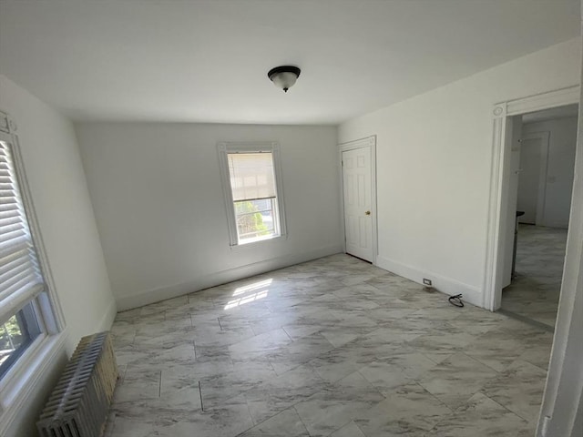 unfurnished bedroom featuring baseboards, radiator heating unit, and marble finish floor