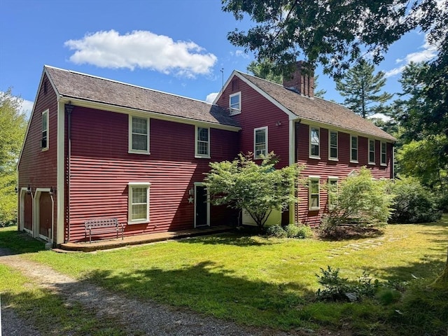 back of house with a lawn and a garage