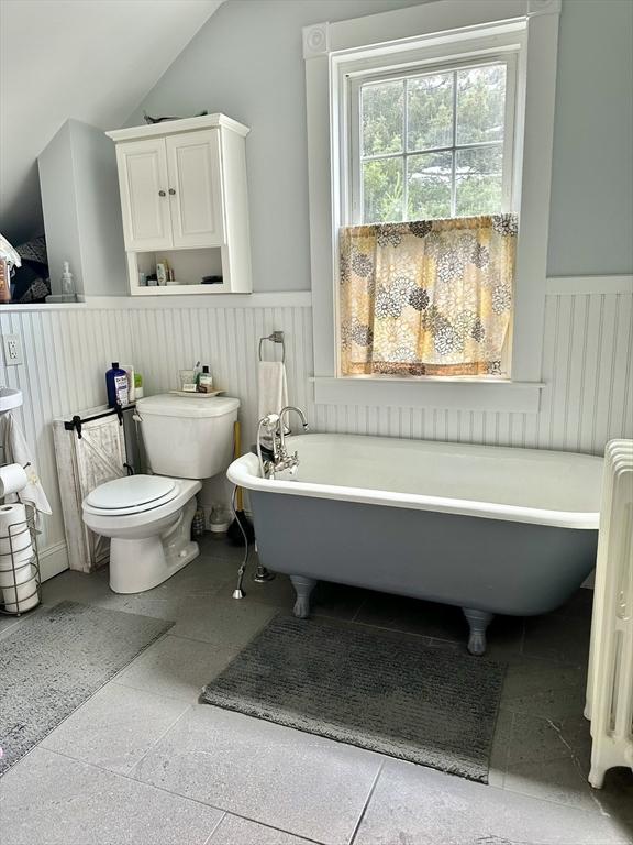 11 Moynan St, New Bedford, MA 02745 - bathroom featuring wainscoting, a freestanding bath, lofted ceiling, toilet, and radiator heating unit
