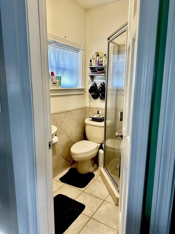 11 Moynan St, New Bedford, MA 02745 - full bathroom with tile walls, tile patterned floors, a shower stall, toilet, and wainscoting