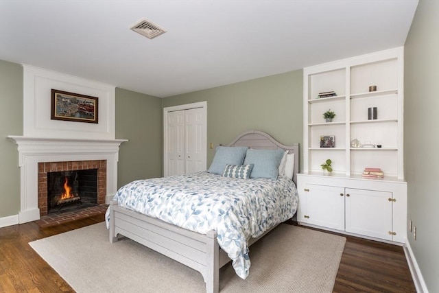 bedroom featuring dark hardwood / wood-style flooring, a closet, and a fireplace