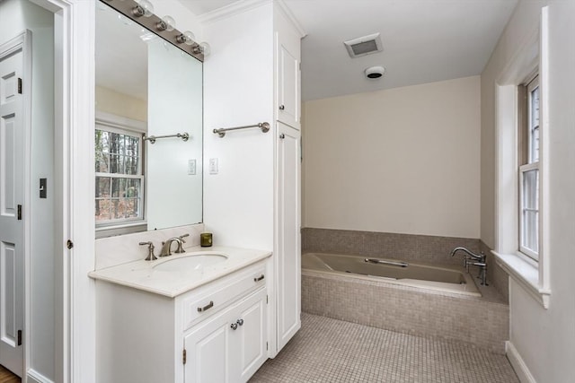 bathroom with tile patterned floors, vanity, and a relaxing tiled tub