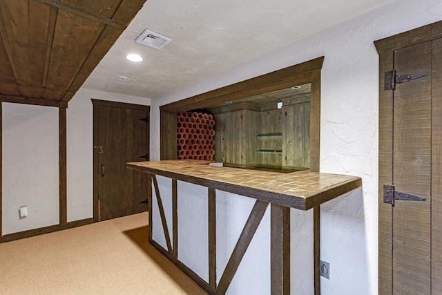 bar with light colored carpet and tile counters