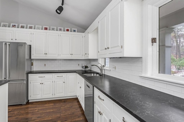 kitchen featuring vaulted ceiling, stainless steel appliances, white cabinetry, and sink