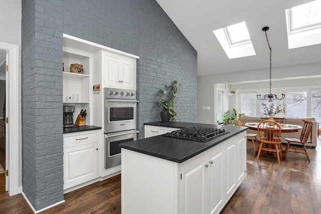 kitchen featuring pendant lighting, lofted ceiling with skylight, white cabinets, black gas stovetop, and stainless steel double oven